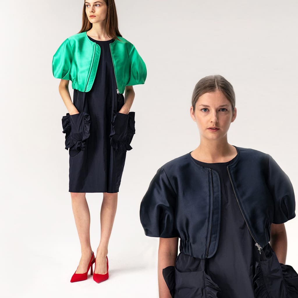 Schwarzes, knielanges Kleid mit aufgesetzten, großen Rüschentaschen und grünel, Satin-Bolero mit kurzen Puffärmeln von Susanne Bommer